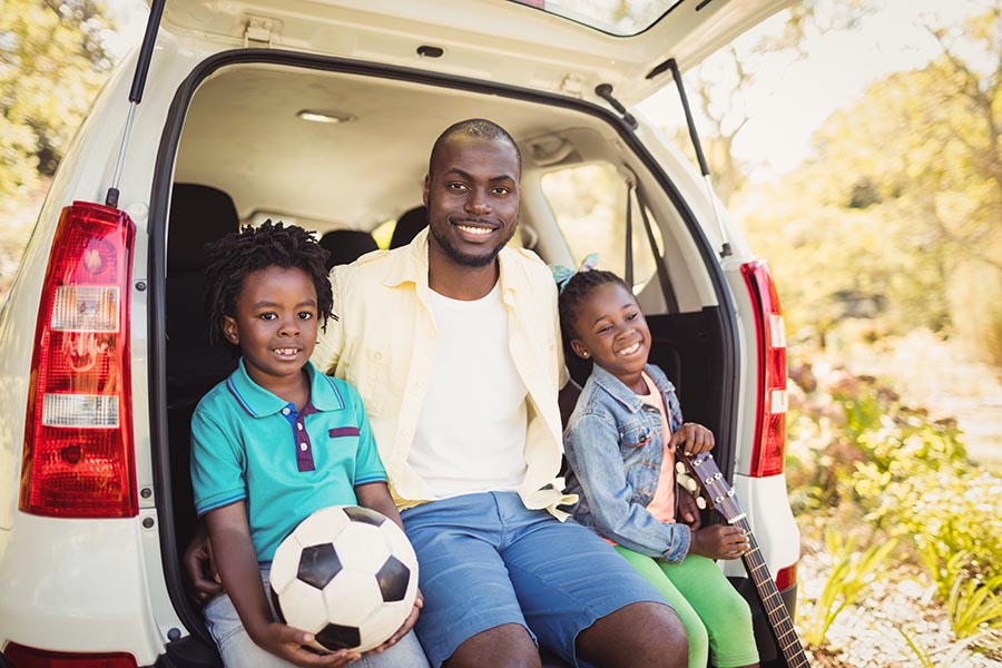 Blog - Father and Two Kids Sitting in the Back of Their Car Holding a Soccer Ball