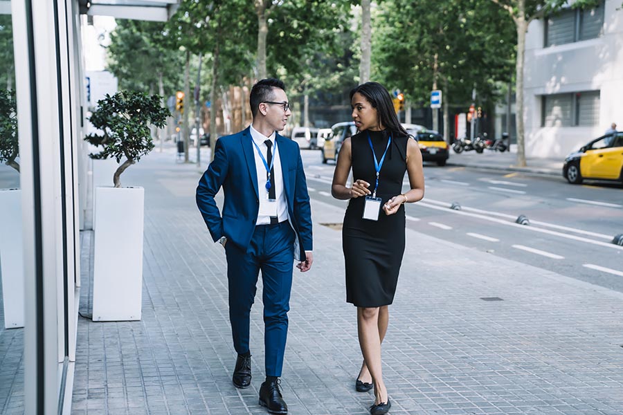 CAM Partners - Two Business Associates Walking on a City Street Wearing Convention Lanyards